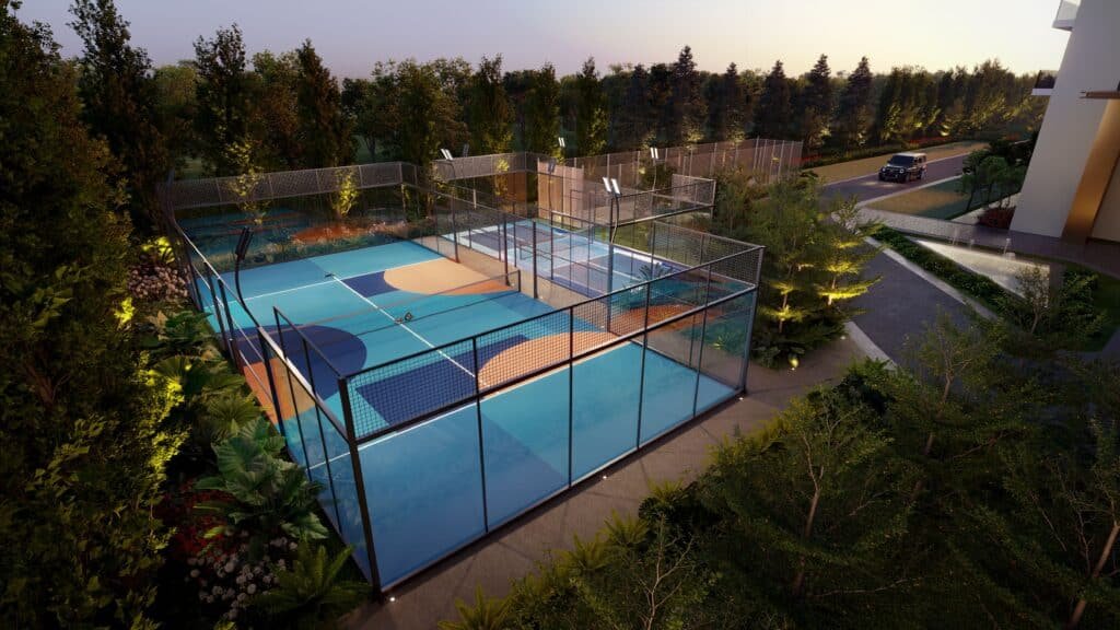 Aerial view of illuminated outdoor padel courts with glass walls, surrounded by trees at dusk.